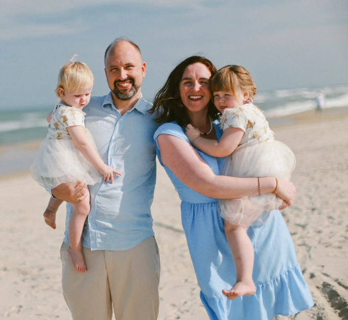 Family posing on a sandy beach with ocean background